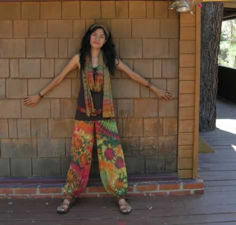 Gigi in harem pants with matching scarf standing at the cabin wall